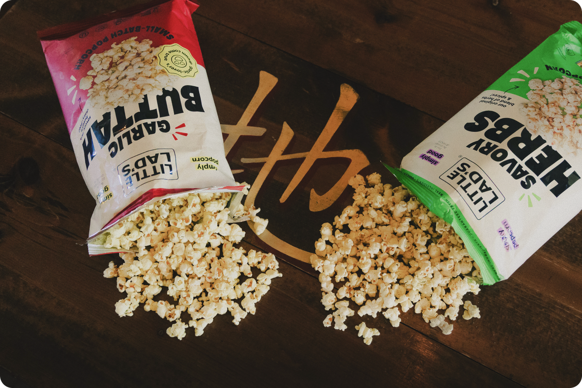 Little Lad's small-batch popcorn bags handcrafted in Vermont including Savory Herbs, Garlic Buttah, and Spicy Dill Pickle on a rustic wooden surface